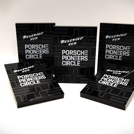 Schwarze Parkschilder mit der Aufschrift 'Reserviert für Porsche Pioneers Circle'.
