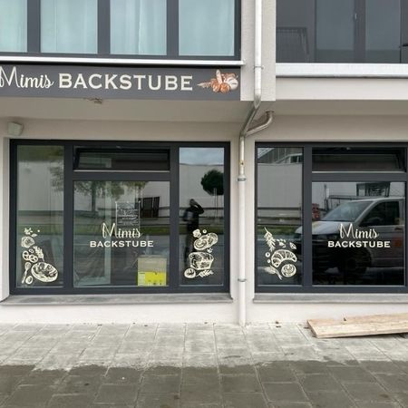 Schaufenster von 'Mimi's Backstube' mit dekorierten Fenstern und einem Schild darüber.
