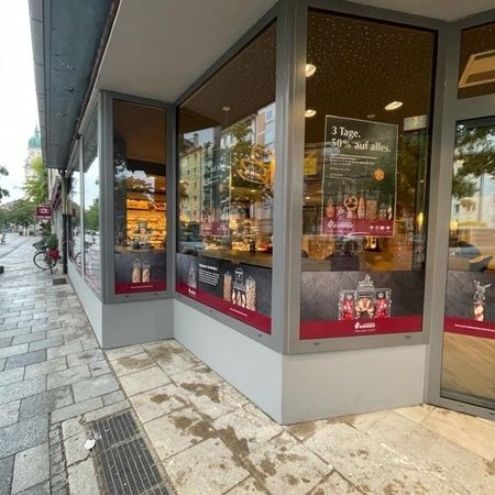Schaufenster mit Verkaufsplakaten, in denen sich die Straße der Stadt auf den Glasscheiben spiegelt.