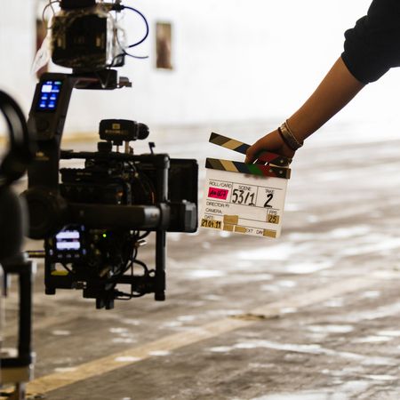 Die Hand einer Person, die eine Filmklappe vor einer Kamera an einem Filmset hält.