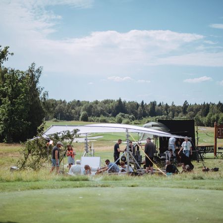 Außenaufnahmen auf einem Golfplatz mit Crew und Ausrüstung.