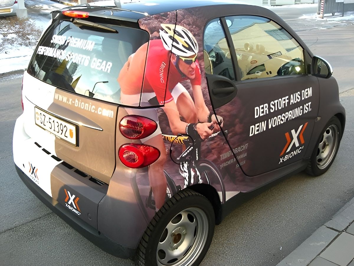 Ein Auto mit Werbegrafiken für X-Bionic-Sportgeräte und einem Teilbild eines Radfahrers.