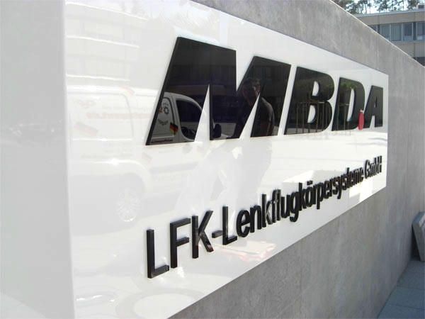 Ein Schild mit den Logos 'MBDA' und 'LFK-Lenkflugkörpersysteme GmbH' auf einer weißen Wand.