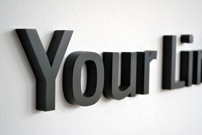 Ein schwarzer 3D-Schriftzug an einer Wand lautet 'Your Link'.