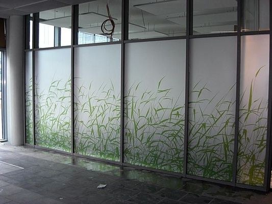 Glastrennwand mit mattiertem Effekt und grünem Bambusdesign in einem Innenbereich.